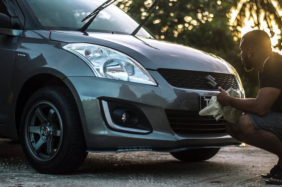 A person cleaning a car's exterior with a microfiber towel