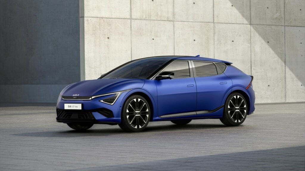 Modern blue electric car parked against a concrete urban wall.